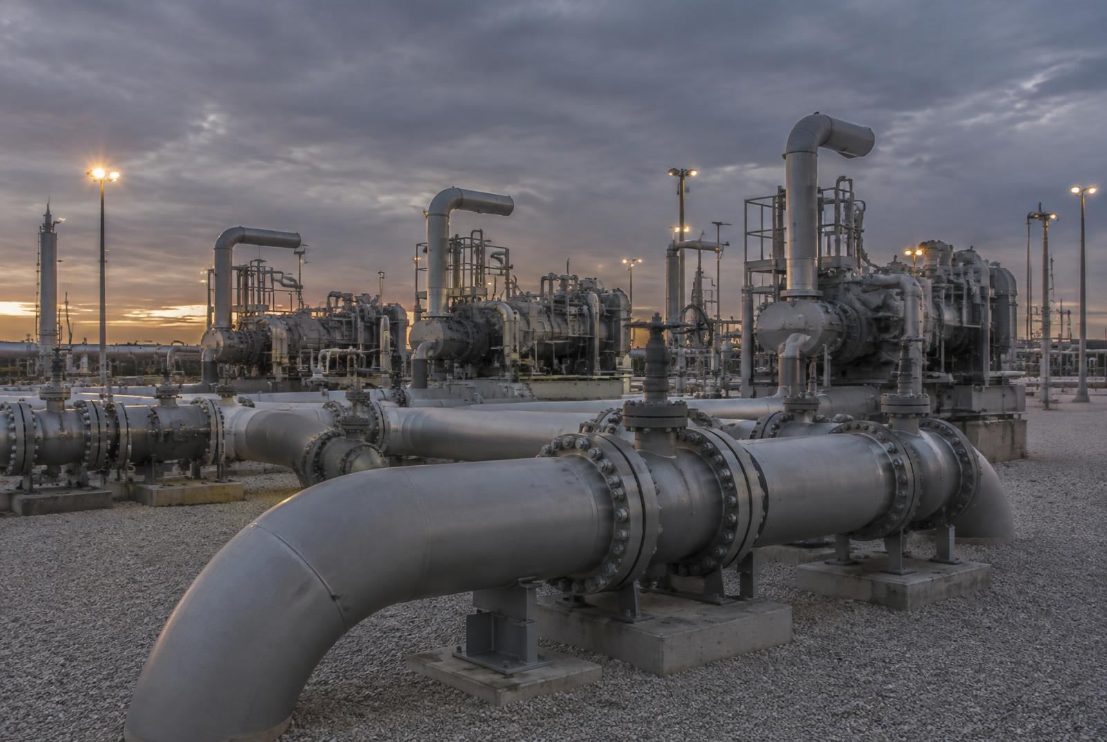 Natural gas compression facility with steel pipework at dusk