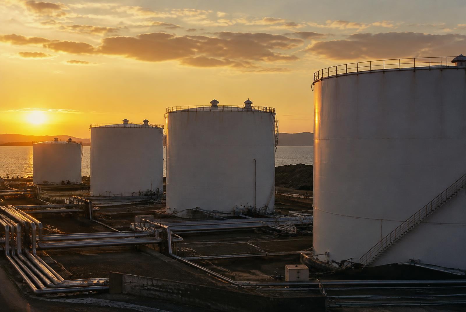 White fuel storage tanks at a coastal terminal at sunset